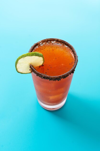 Cóctel casero de michelada con cerveza, jugo de lima, salsa picante, borde salado y jugo de tomate.