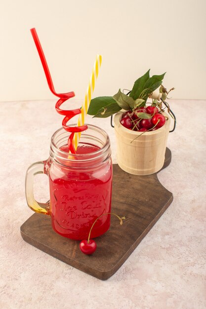 Un cóctel de cereza roja de vista frontal con pajitas y cerezas en el escritorio rosa jugo de bebida de color de fruta