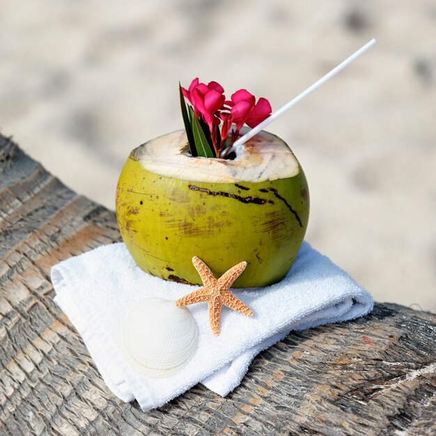 Cóctel de coco con pajita en una palmera en la playa