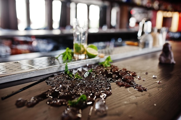 Cóctel derramado alcohólico con menta y hielo en la mesa del bar