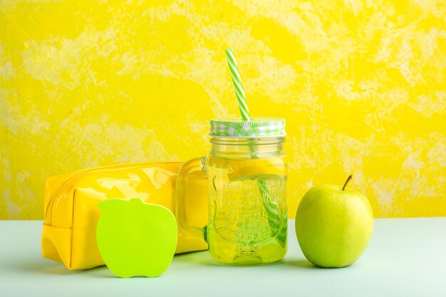 Cóctel fresco de vista frontal con manzana verde y caja de bolígrafos sobre superficie amarilla