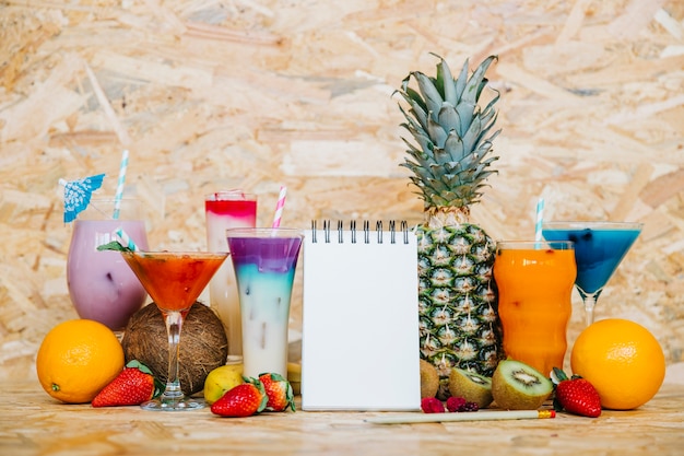 Cóctel y frutas tropicales con libreta en blanco