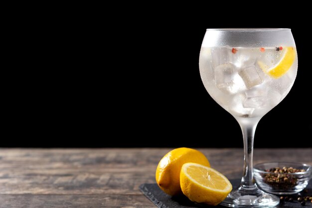 Cóctel de gin tonic en un vaso sobre una mesa de madera