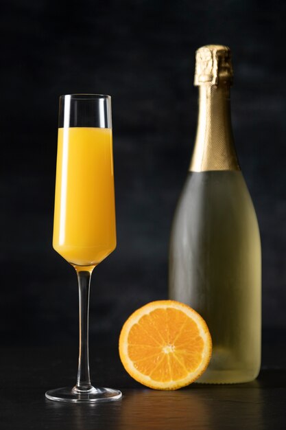 Cóctel de mimosa con botella y rodaja de naranja.