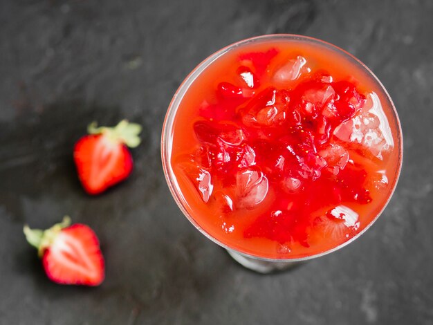Cóctel rojo frío con hielo y fresa fresca.