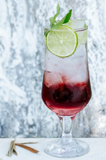 Cóctel rojo con rodajas de limón y hojas de menta.