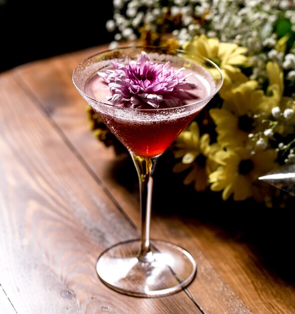 Cóctel rosa adornado con flores en copa de martini