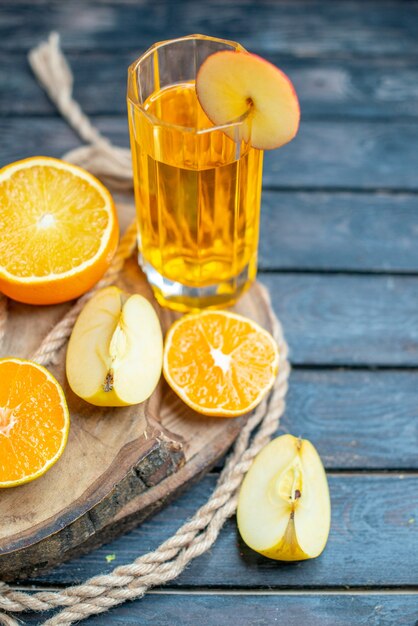 Cóctel de vista frontal cortadas naranjas y manzanas en tablero de madera en la oscuridad