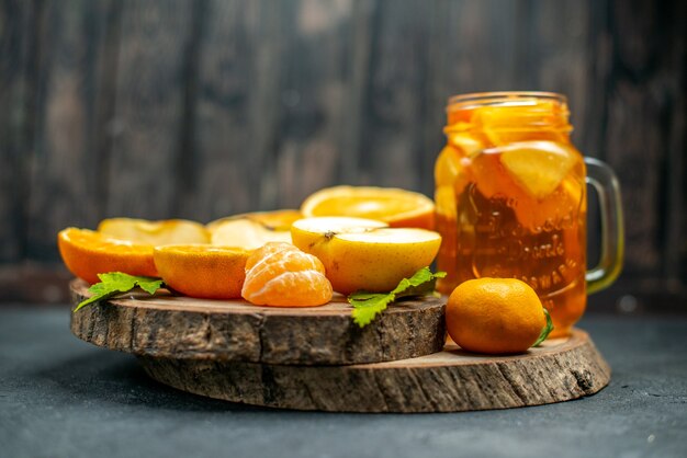 Cóctel de vista frontal cortar manzanas naranjas en la oscuridad