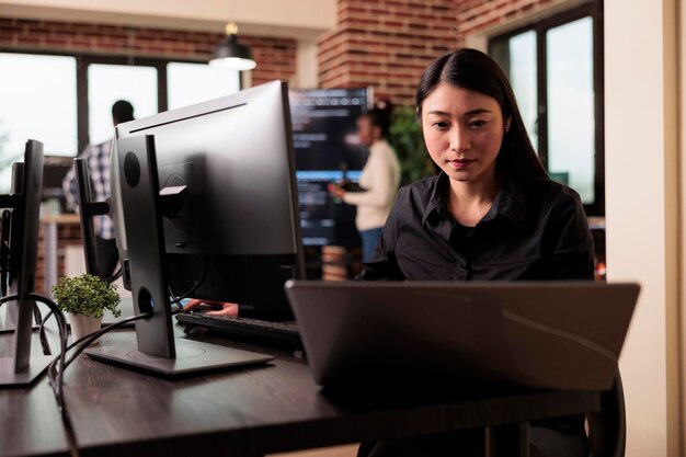 Codificador independiente escribiendo código de servidor de aprendizaje automático, sentado en la mesa de escritorio en una compañía de software. Desarrollador de software trabajando en un sistema de base de datos con script de codificación en él desarrollando oficina