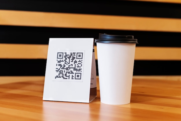 Foto gratuita código qr y taza de café para llevar en una mesa