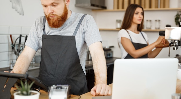 Coffee Business Concept Joven y apuesto barman barman barista o gerente que publica el pedido del invitado en el menú de la tableta digital en la cafetería moderna