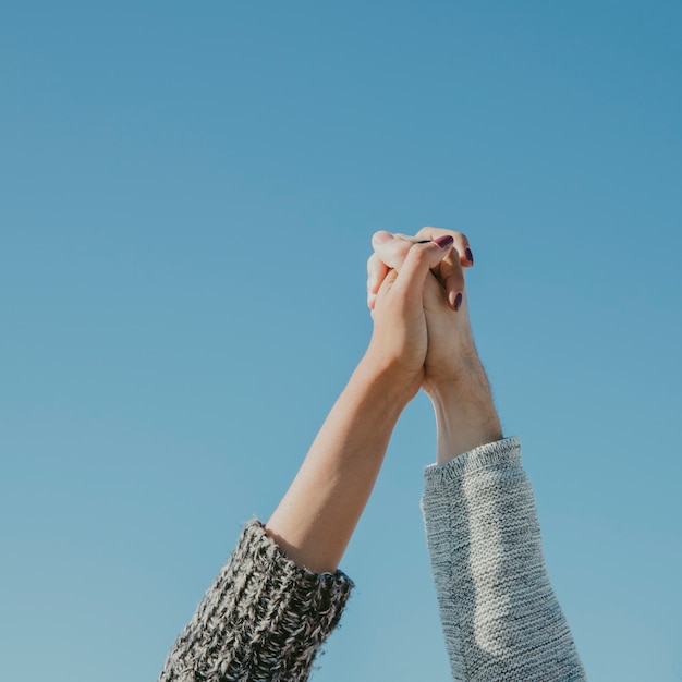 Cogiéndose las manos enfrente de cielo