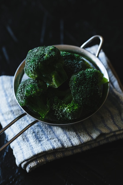 Colador de brotes de brócoli sobre fondo negro.