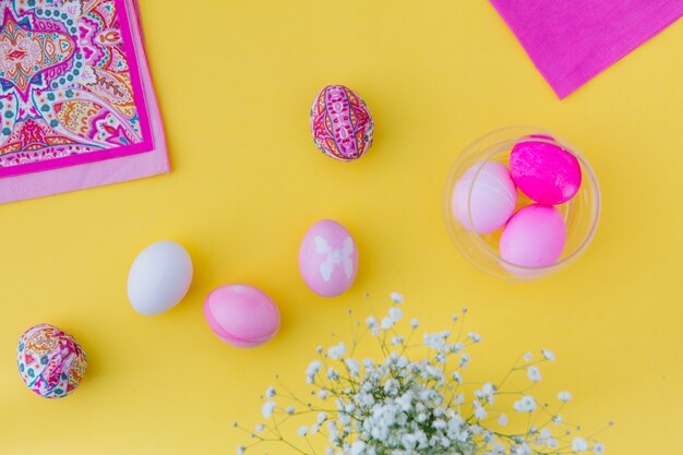 Colección de huevos de Pascua rosa en un tazón cerca de servilletas y flores