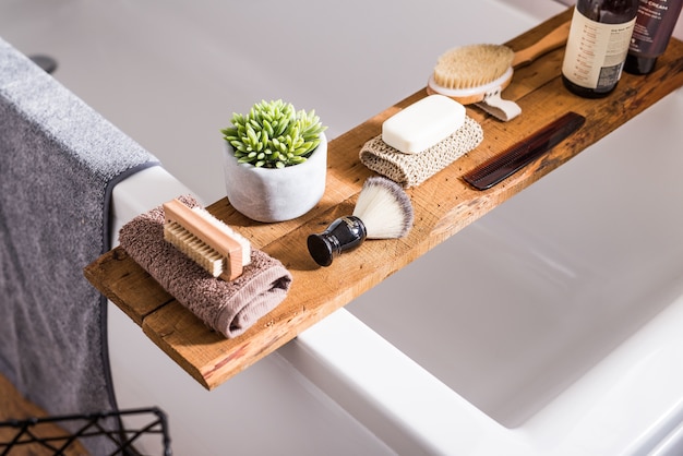 Colección de toallas de baño, brocha de afeitar, cepillo, champús y jabón en una madera