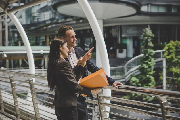 Colega de negocios hablando y viendo documentos al aire libre