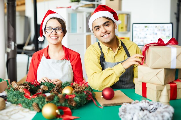 Colegas alegres con regalos y corona de Navidad