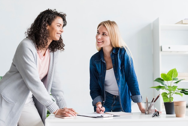 Colegas amigables discutiendo el trabajo y riéndose de la oficina