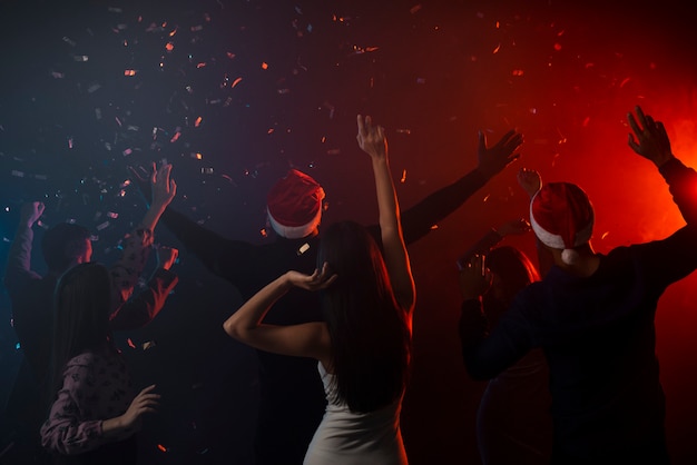 Colegas bailando en confeti en la fiesta de año nuevo