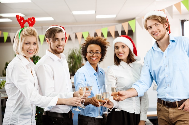 Foto gratuita colegas celebrando la fiesta de navidad en la oficina bebiendo champán sonriendo.