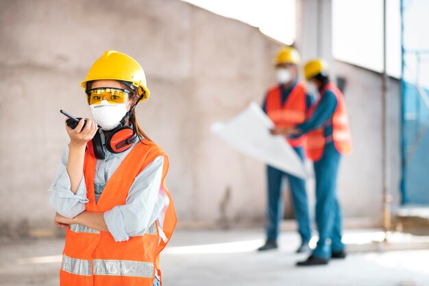 Colegas con equipo de seguridad trabajando con planos