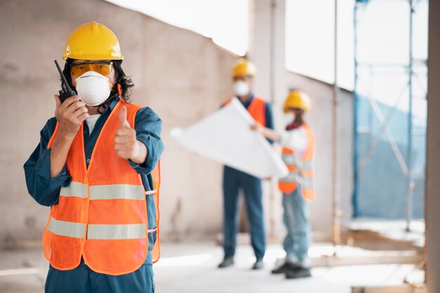 Colegas con equipo de seguridad trabajando con planos
