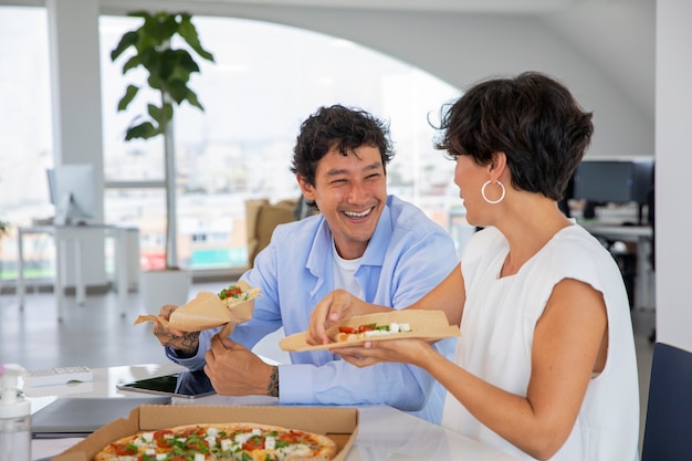 Foto gratuita colegas felices de tiro medio con pizza
