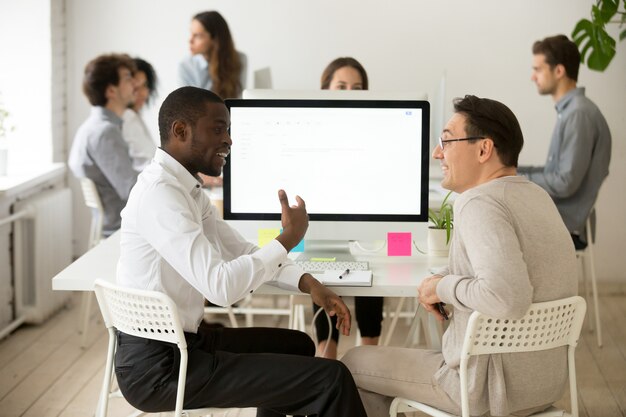 Colegas masculinos diversos sonrientes amistosos que tienen conversación agradable en el trabajo