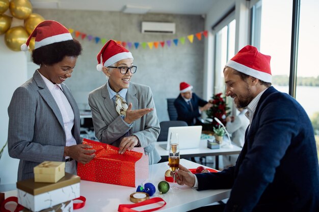 Colegas de negocios felices envolviendo regalos de Navidad en la fiesta de la oficina
