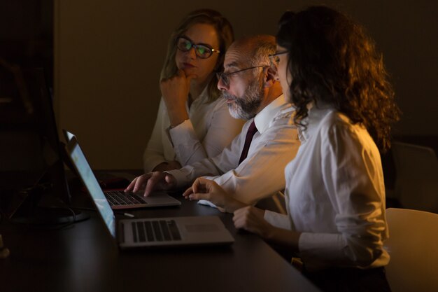 Colegas de negocios que usan computadoras portátiles en la noche