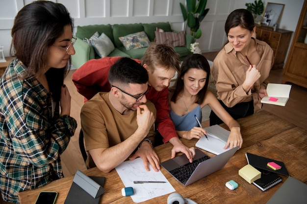 Colegas que buscan información usando una computadora portátil y cuadernos en una sesión de estudio