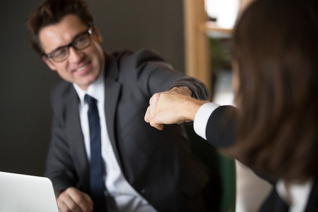 Colegas que dan puñetazos celebrando logros empresariales compartidos