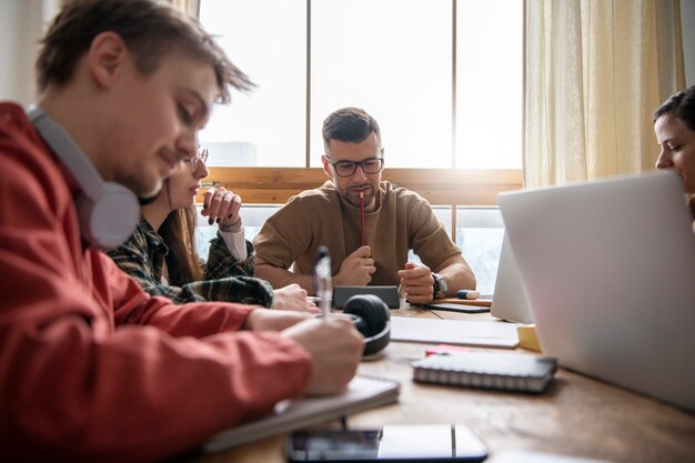 Colegas que estudian en una biblioteca usando computadoras portátiles y portátiles