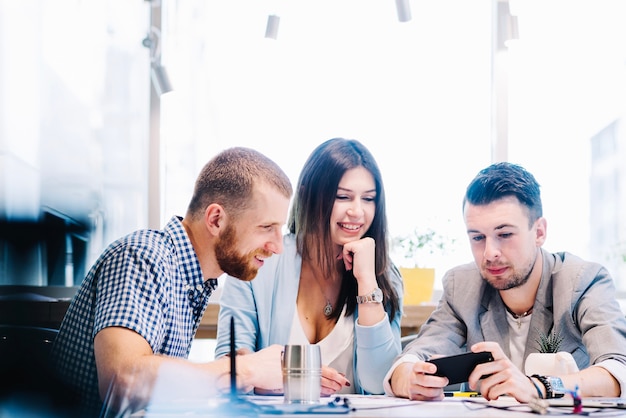 Colegas que miran smartphone durante el trabajo