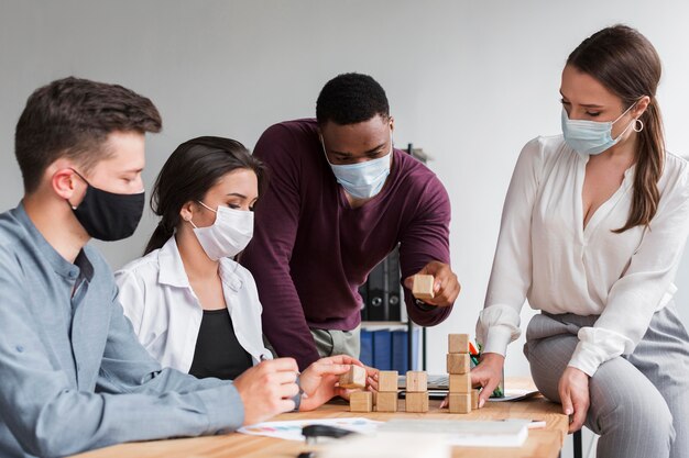 Colegas que tienen una reunión en la oficina durante una pandemia con máscaras médicas en