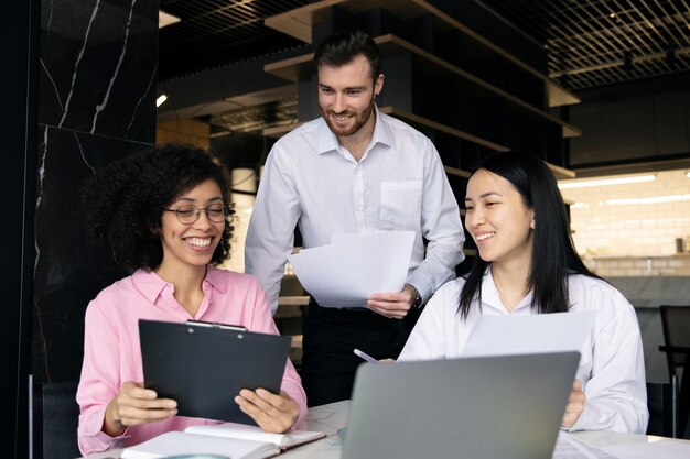 Colegas que trabajan juntos usando una computadora portátil y documentos