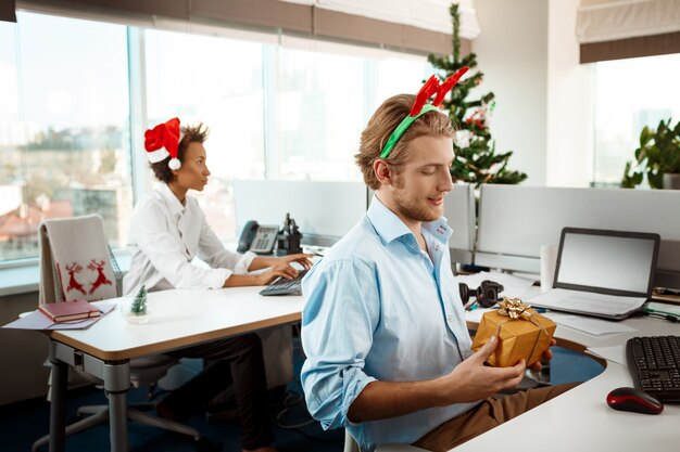 Colegas que trabajan en la oficina el día de Navidad dando regalos.