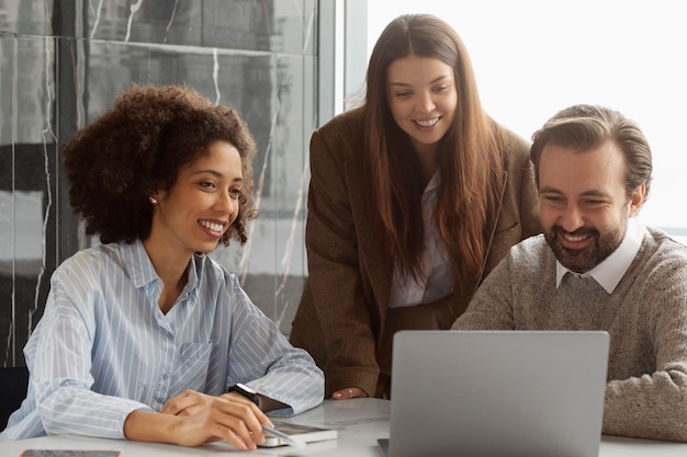 Colegas sonrientes de tiro medio en el trabajo