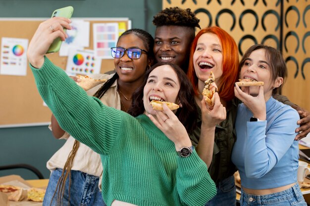 Colegas de tiro medio comiendo pizza en el trabajo