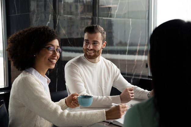 Foto gratuita colegas trabajando juntos usando documentos y tomando café