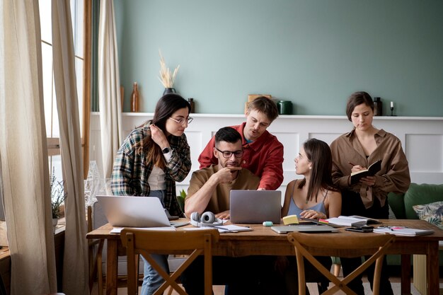 Colegas usando portátiles y cuadernos para aprender en una sesión de estudio