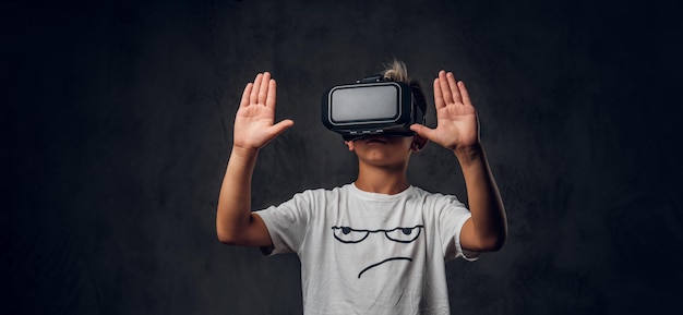 Un colegial bonito y joven está jugando un videojuego virtual con gafas especiales.