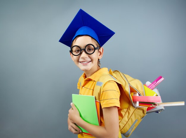 Colegial feliz con gafas negras y gorro de graduación