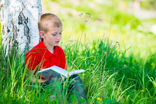 Colegial leyendo el libro en la naturaleza.