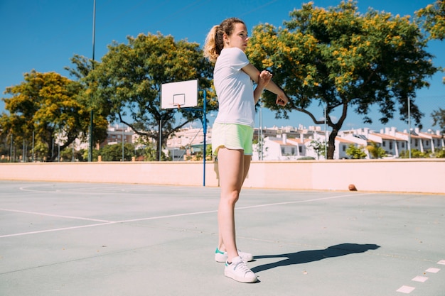 Colegiala adolescente estirando los brazos en el campo de deportes