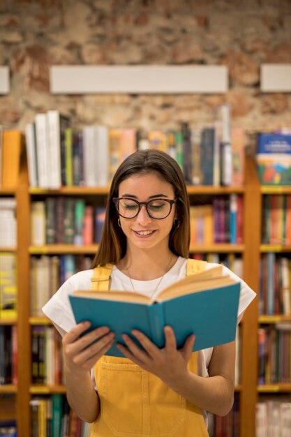 Colegiala adolescente mirando el libro de la biblioteca