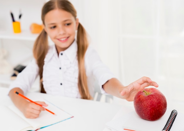 Colegiala alegre sonriendo y tomando manzana roja