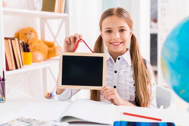 Colegiala alegre en uniforme estudiando en clase