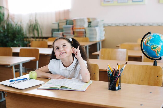 Colegiala apuntando hacia arriba en la clase